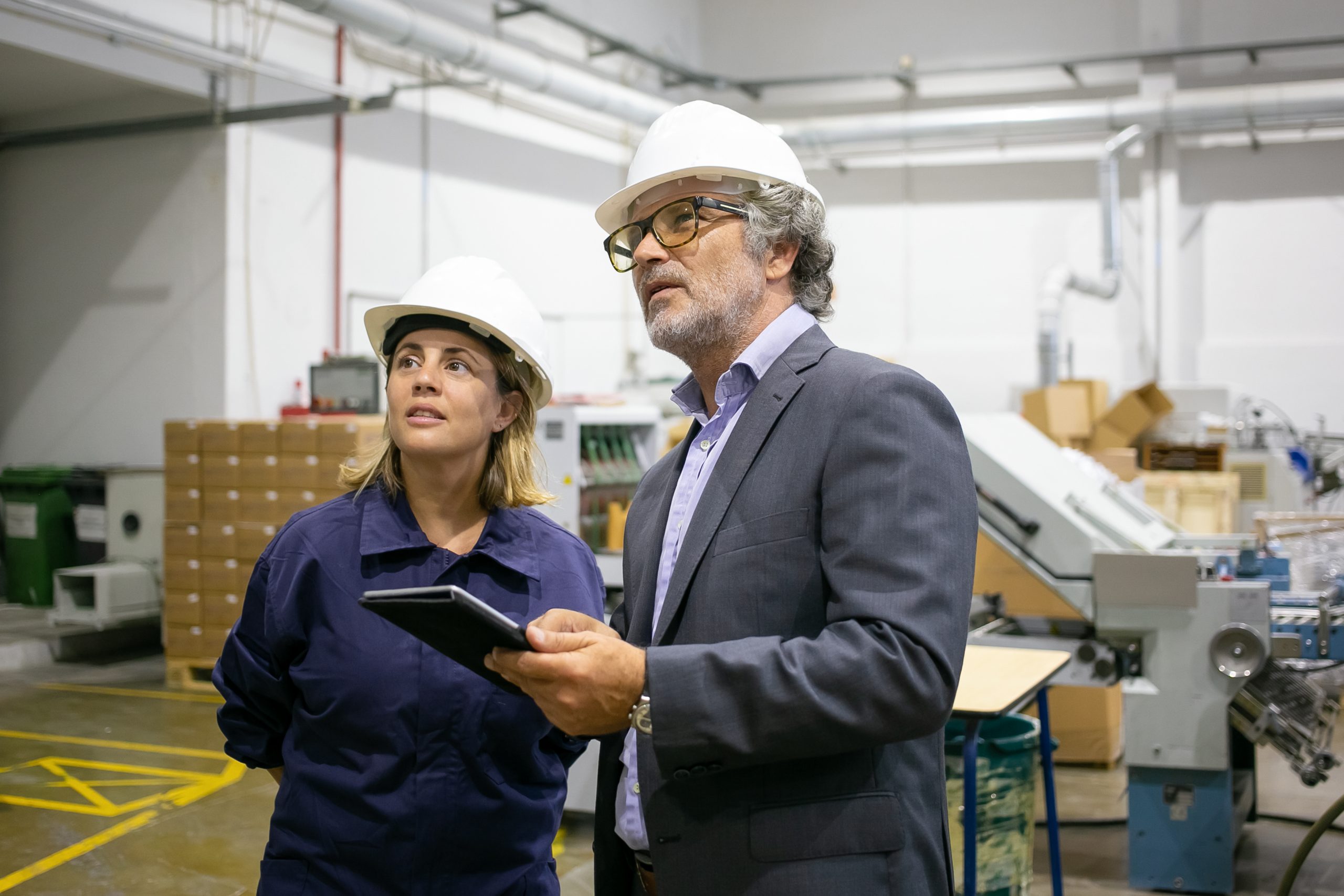 Confident bearded supervisor talking with female plant worker