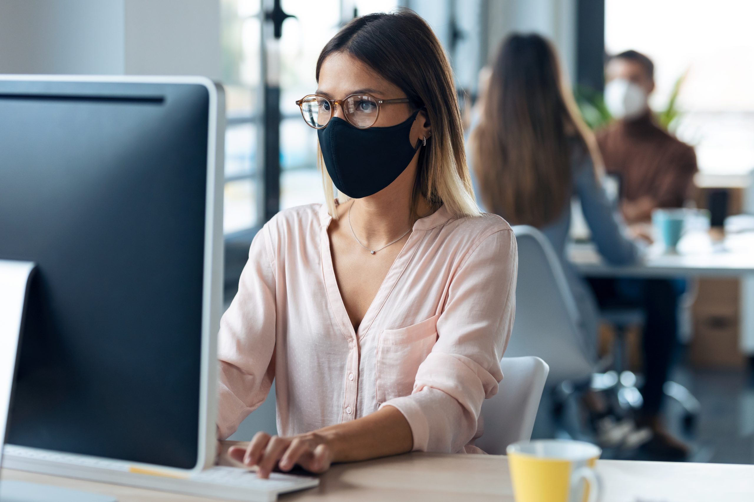 Beautiful young business woman wearing a hygienic face mask work